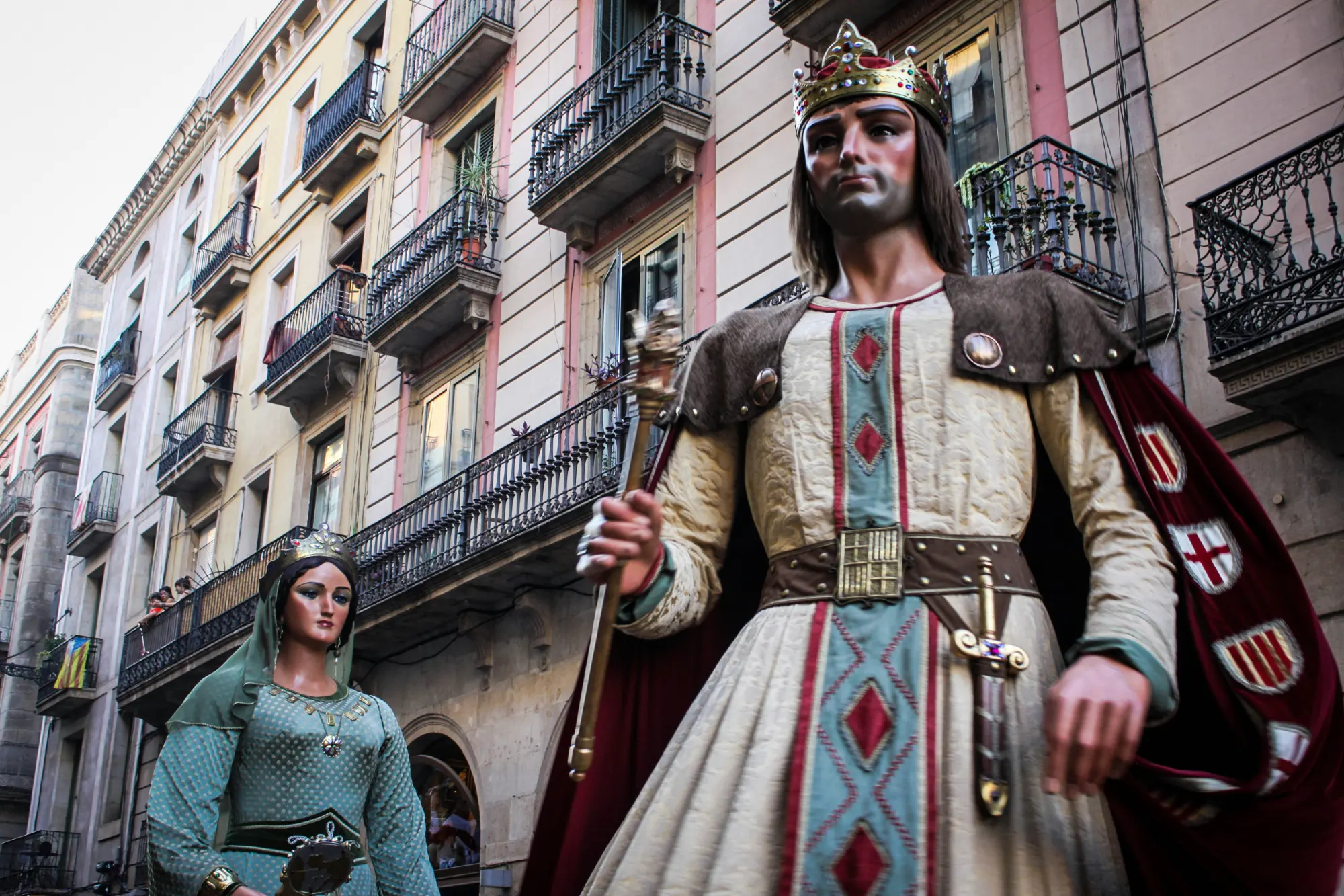 Traditional giant papier-mâché figures, known as Gegants, parading through a narrow street in Barcelona.