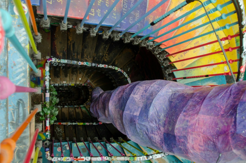 Top-down view of the colorful spiral staircase at 59 Rivoli, featuring rainbow railings and painted steps.