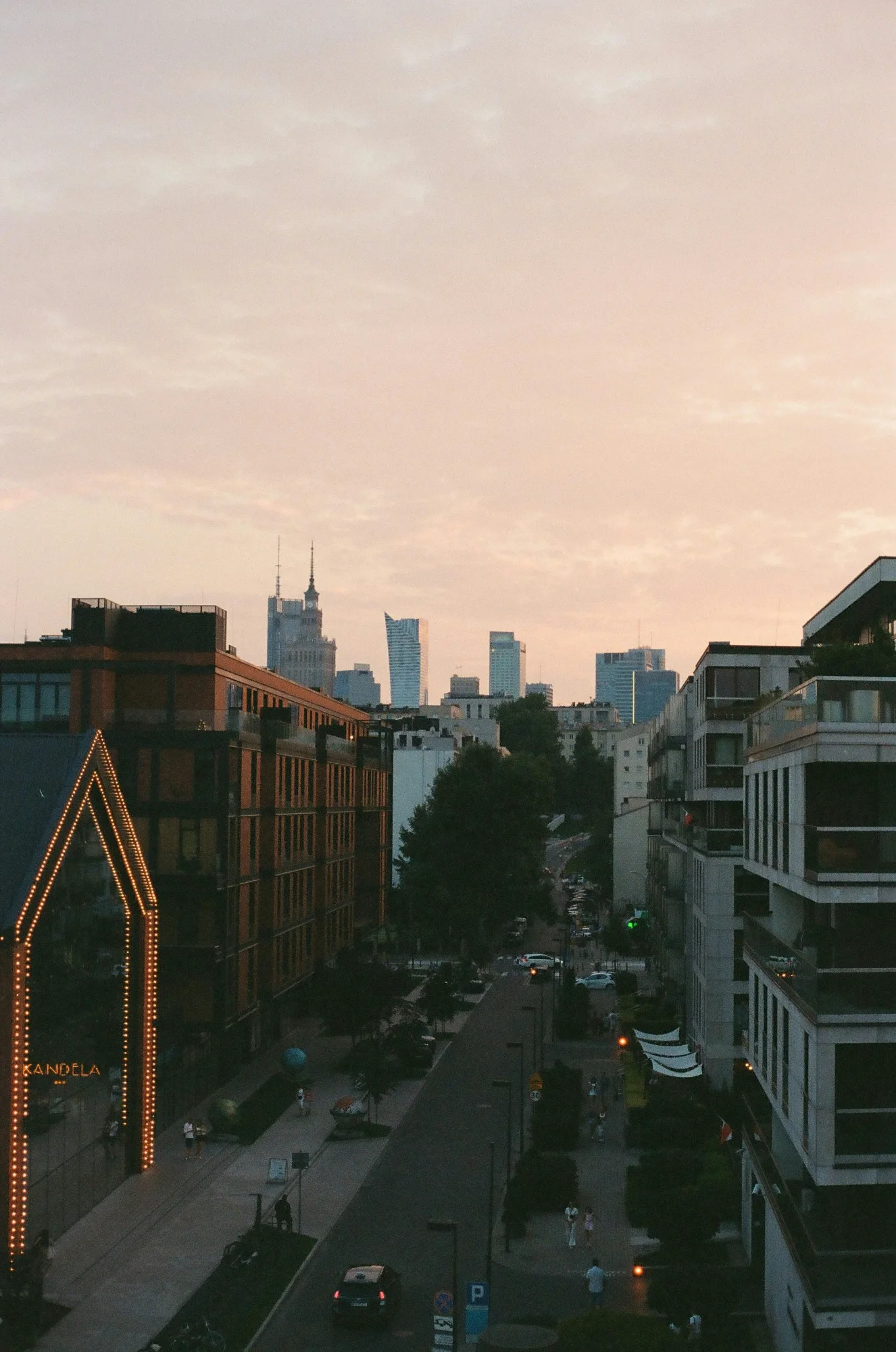 Evening view of a Warsaw street with Elektrownia Powiśle on the left and the Palace of Culture skyline in the distance.