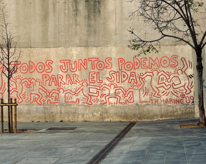 Red Keith Haring mural in Barcelona reading Todos juntos podemos parar el sida with dancing figures.