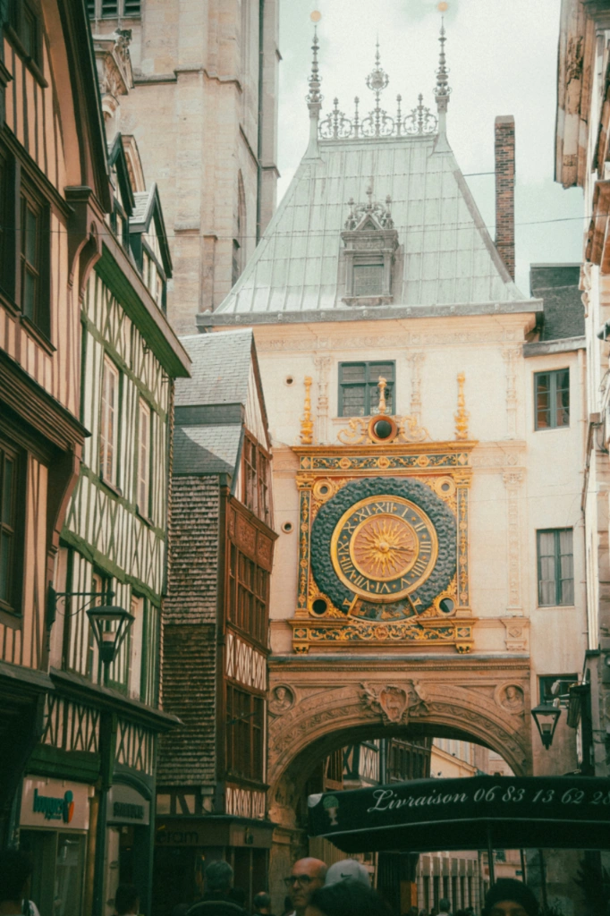 The Gros-Horloge astronomical clock above a street lined with half-timbered houses in Rouen.