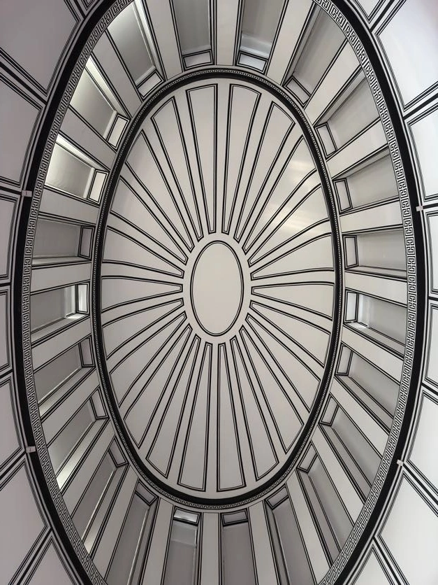 White oval ceiling with radiating black lines, a central oval, and rectangular panels creating an optical illusion of depth.